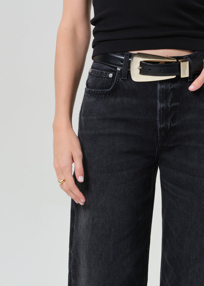 Person wearing a black sleeveless top and black jeans on a plain background