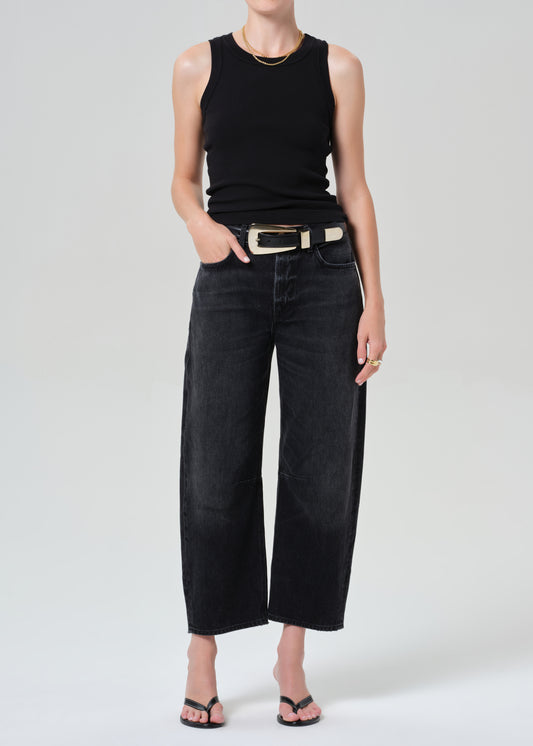 Person wearing a black sleeveless top and black jeans on a plain background