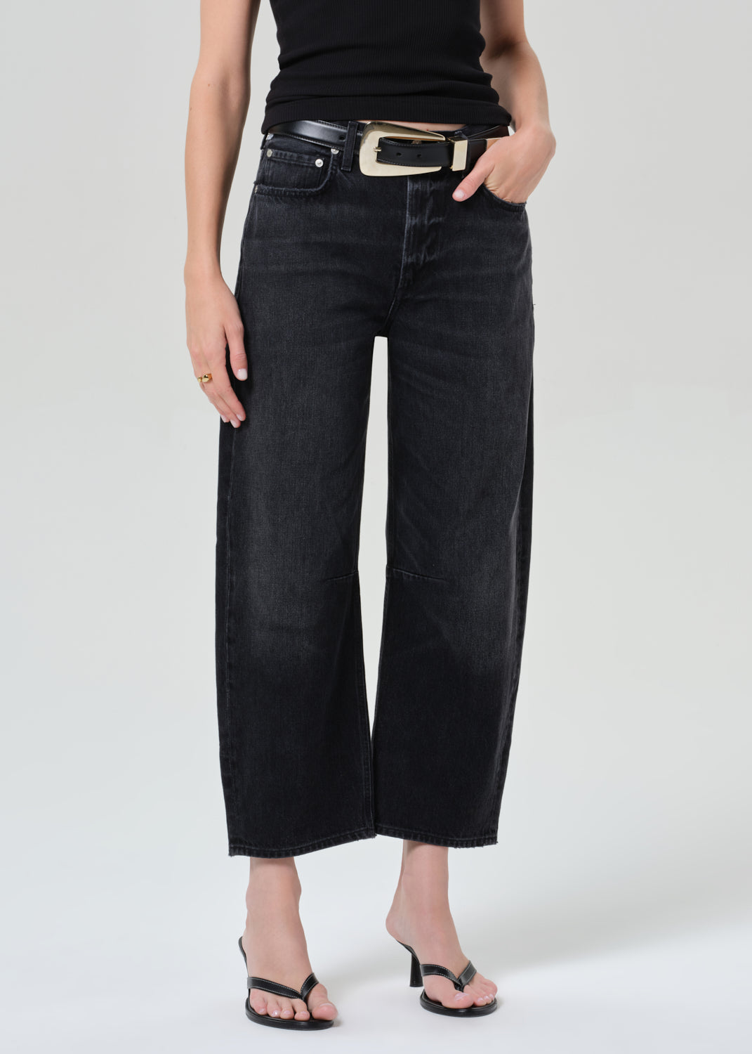 Person wearing a black sleeveless top and black jeans on a plain background