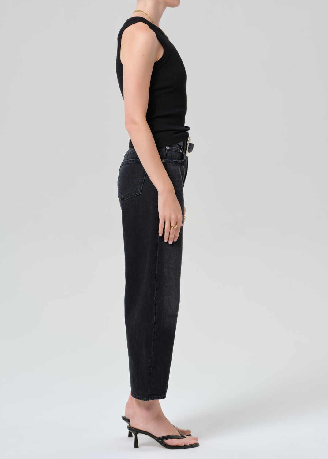 Person wearing a black sleeveless top and black jeans on a plain background