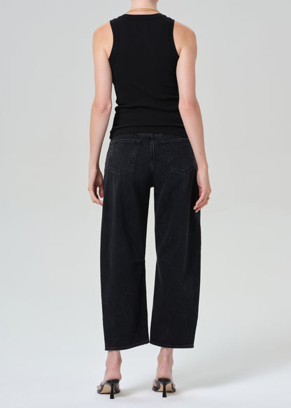 Person wearing a black sleeveless top and black jeans on a plain background