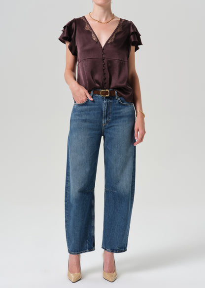 Person wearing brown top with blue pants on a grey background