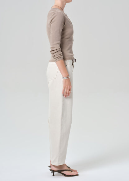 Person wearing a brown long-sleeve shirt and off-white jeans on a plain background