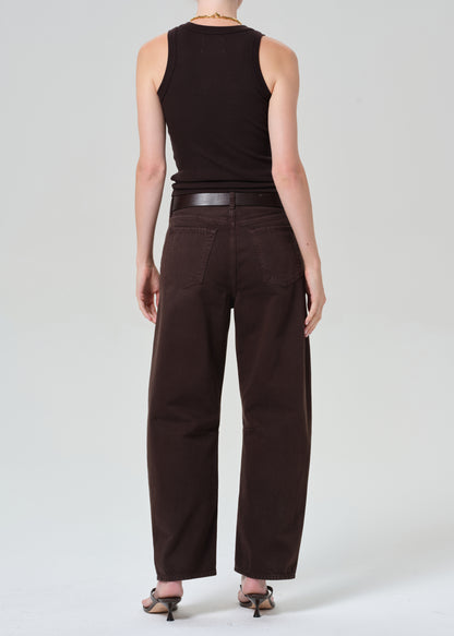 Person wearing a brown sleeveless top and brown pants on a plain background