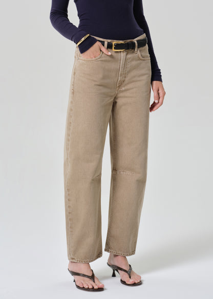 Person wearing a navy turtleneck and beige jeans on a grey background