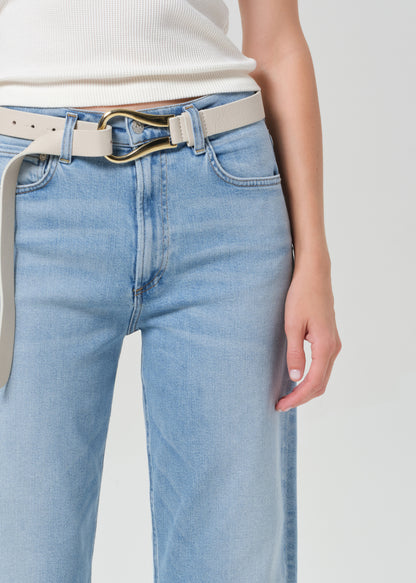 Light blue jeans with a beige belt on a plain background