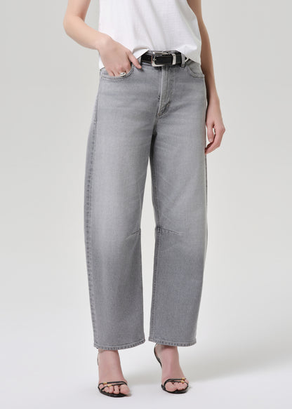 Person wearing grey jeans and a white top on a grey background