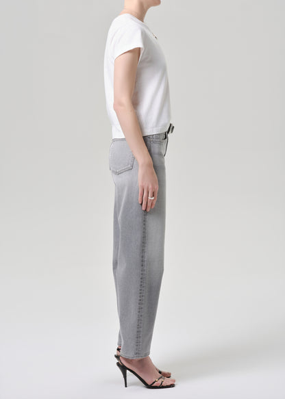 Person wearing a white t-shirt and grey jeans on a grey background