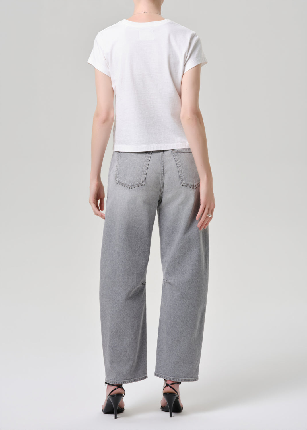 Person wearing a white t-shirt and grey wide-leg pants on a grey background