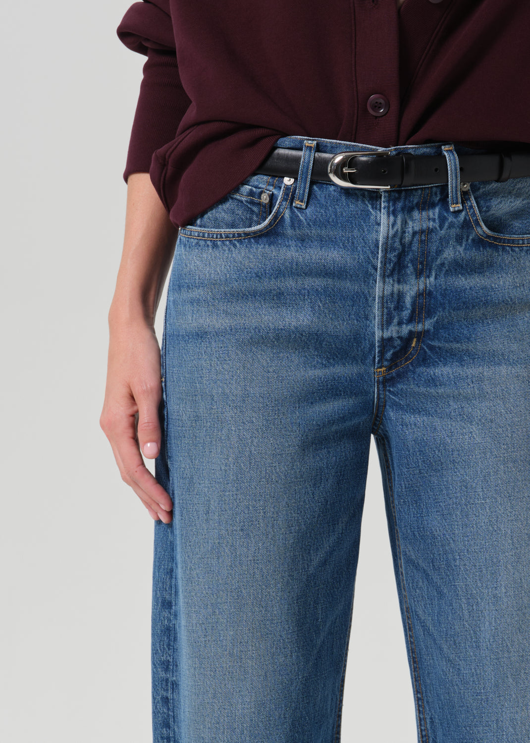 Close up shot of blue pants and a black belt on a grey background