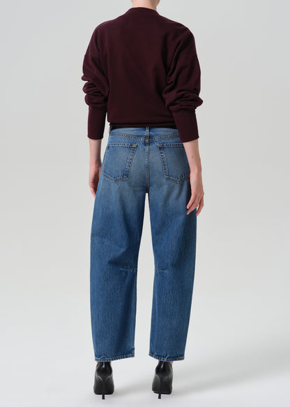 Person wearing burgundy cardigan and a blue pant on a grey background