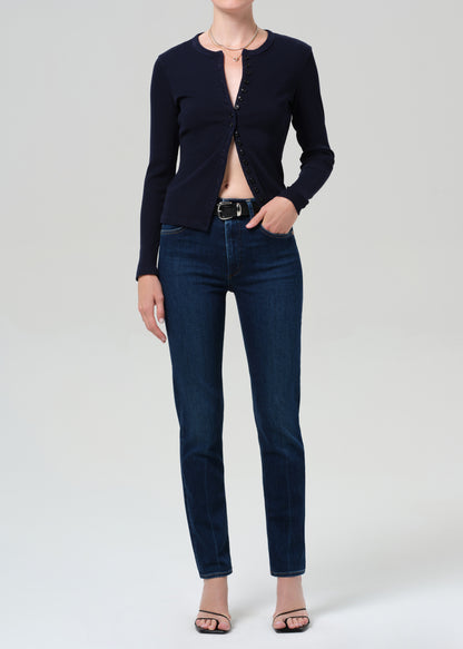 Person wearing a navy cardigan and dark blue jeans on a light gray background