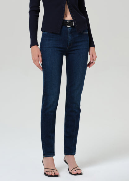 Person wearing a navy sweater and dark blue jeans on a grey background