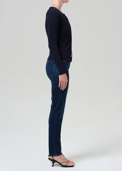Person wearing a navy sweater and dark blue jeans on a grey background