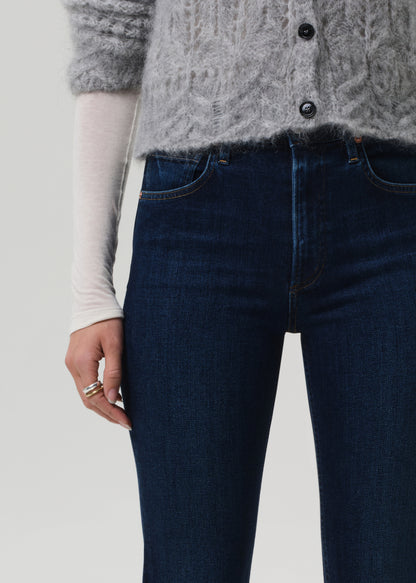 Person wearing dark blue jeans and a gray patterned cardigan on a light background