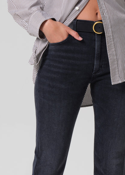 Person wearing a gray striped shirt and black jeans on a grey background