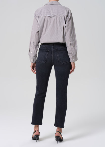 Person wearing a gray striped shirt and black jeans on a grey background