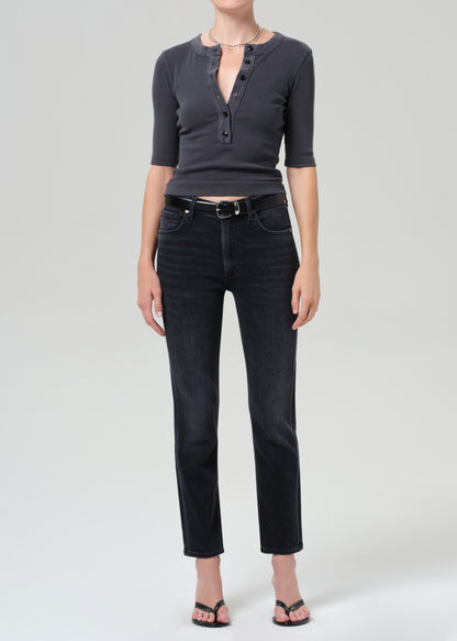 Person wearing a dark gray henley shirt and black jeans on a grey background