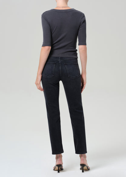 Person wearing a dark gray henley shirt and black jeans on a grey background