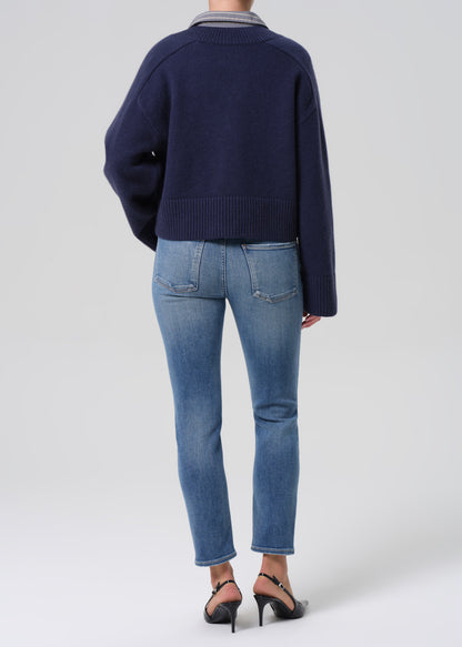 Person wearing a navy sweater and blue jeans on a white background