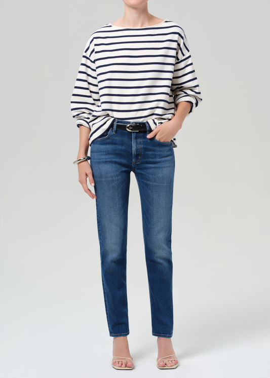 Person wearing a striped shirt and blue jeans on a grey background