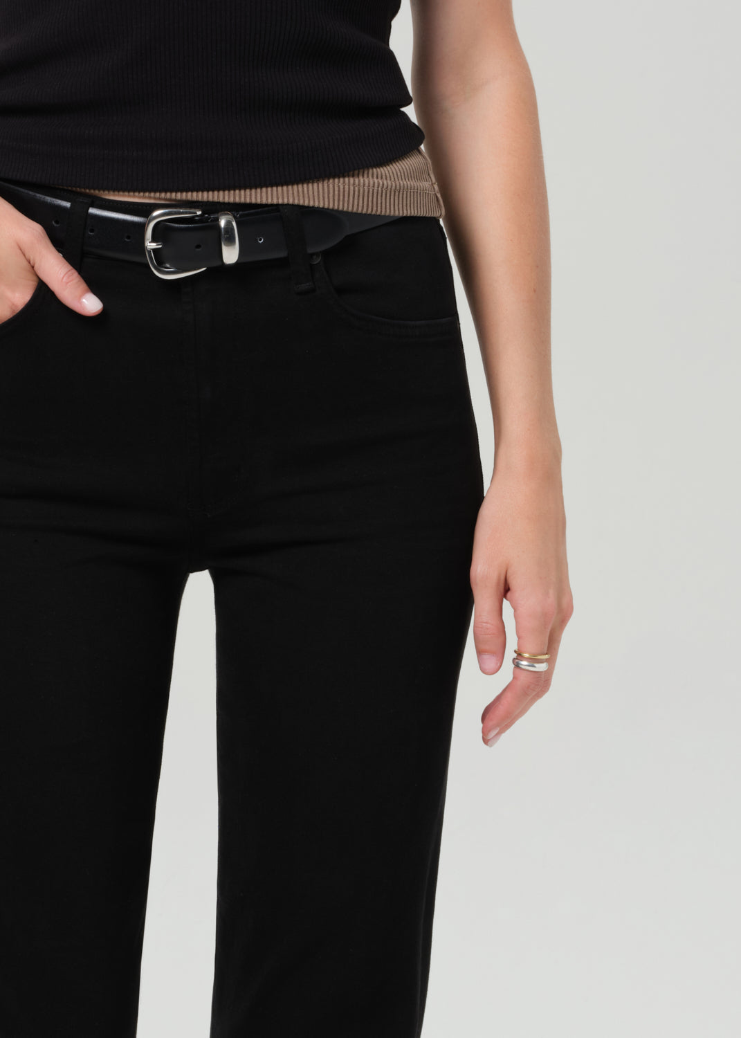 Person wearing a black sleeveless top and black pants on a plain background