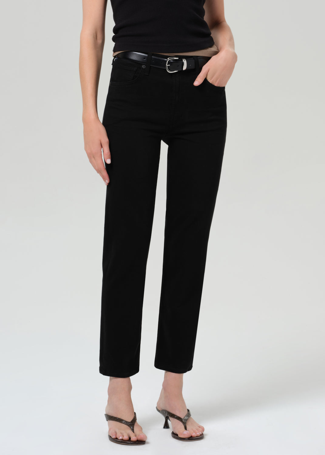 Person wearing a black sleeveless top and black pants on a plain background