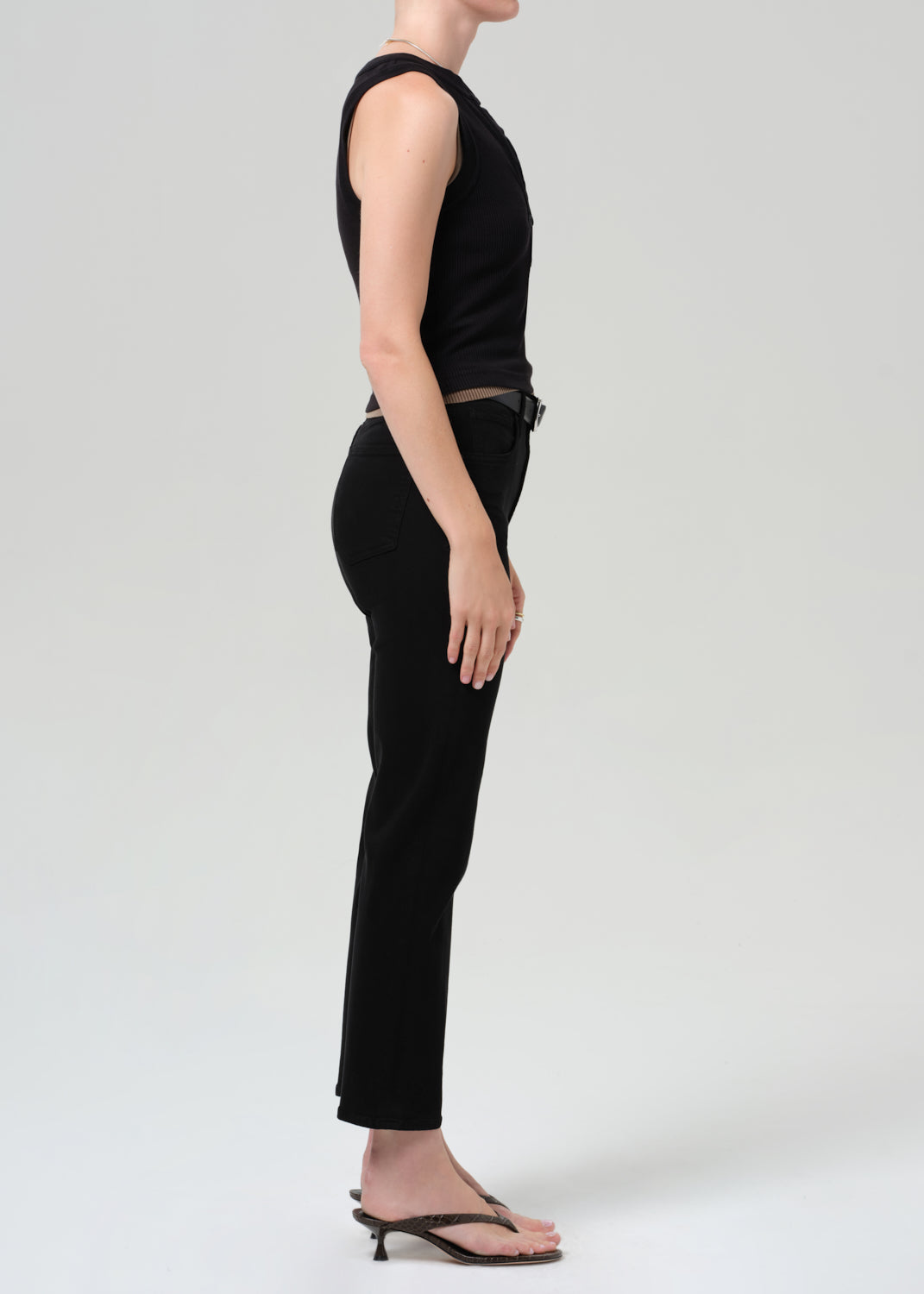 Person wearing a black sleeveless top and black pants on a plain background