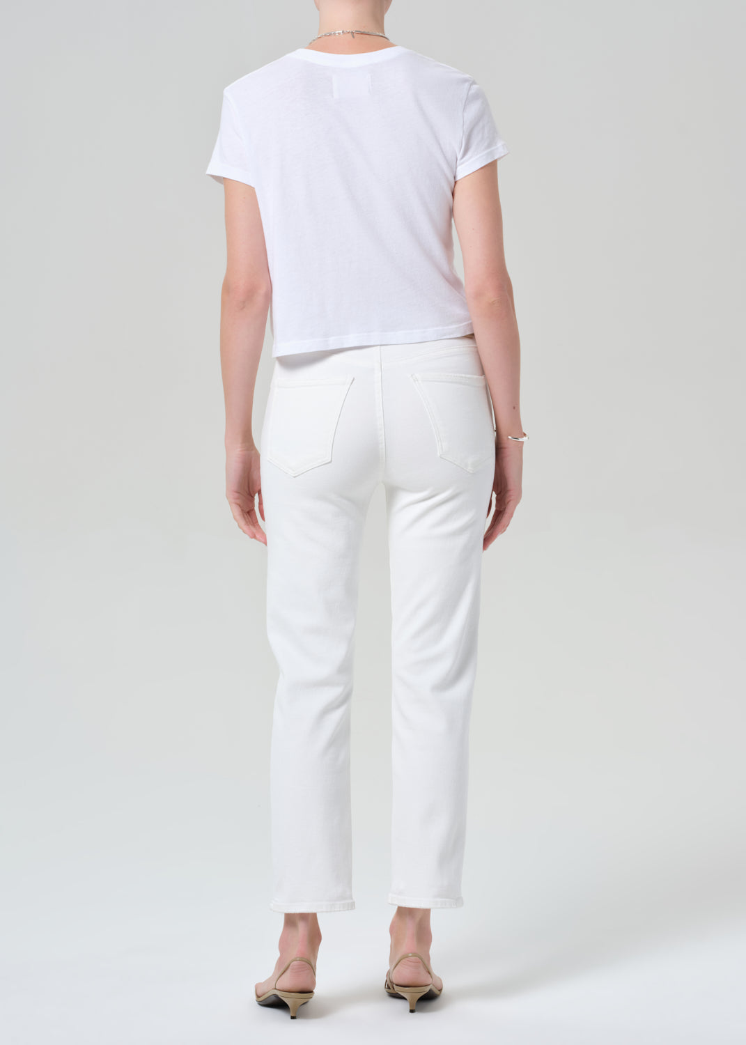 Person wearing a white t-shirt and white jeans on a light gray background