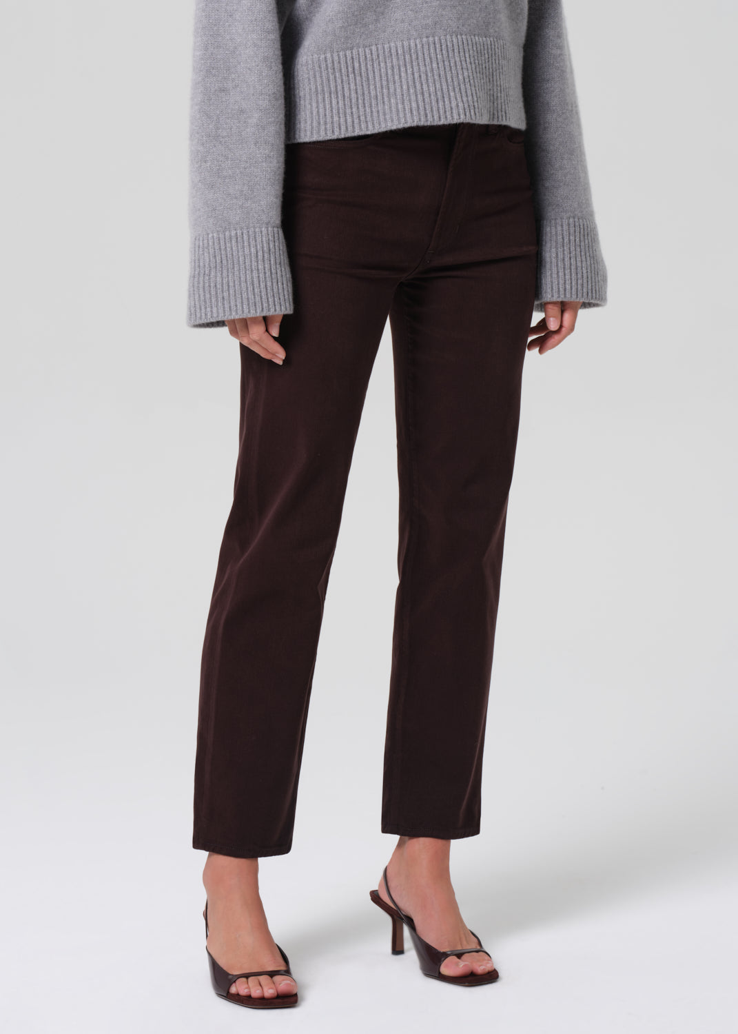 Person wearing brown pants and a gray sweater on a white background