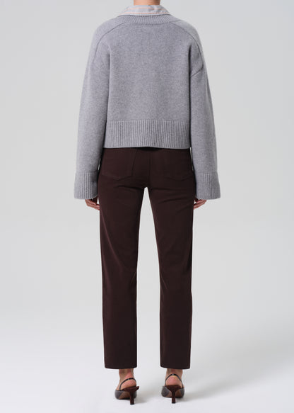 Person wearing a gray sweater and brown pants on a white background