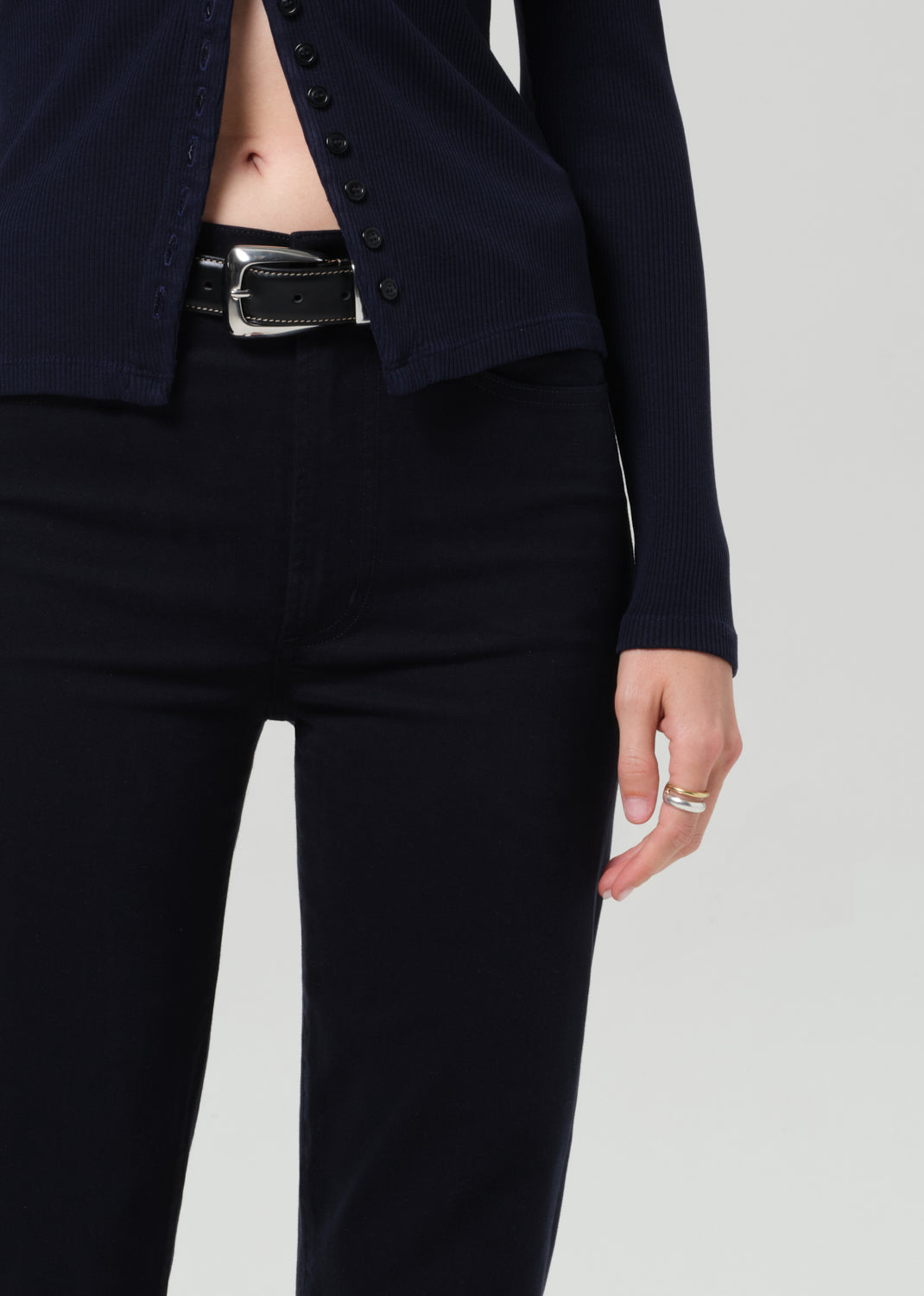 Person wearing a navy navy cardigan and navy pants on a grey background