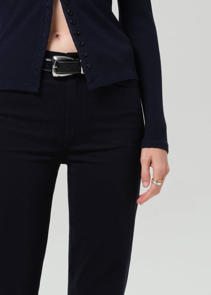 Person wearing a navy navy cardigan and navy pants on a grey background