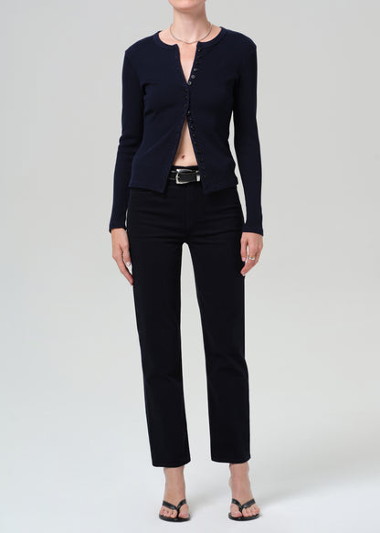 Person wearing a navy navy cardigan and navy pants on a grey background