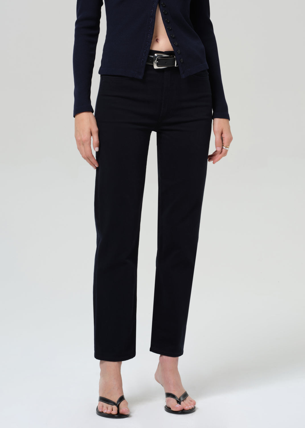 Person wearing a navy navy cardigan and navy pants on a grey background