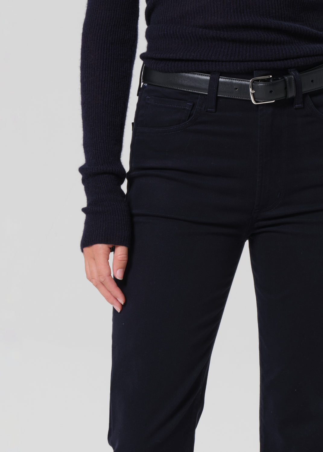 Person wearing a navy long-sleeve top and navy pants on a grey background