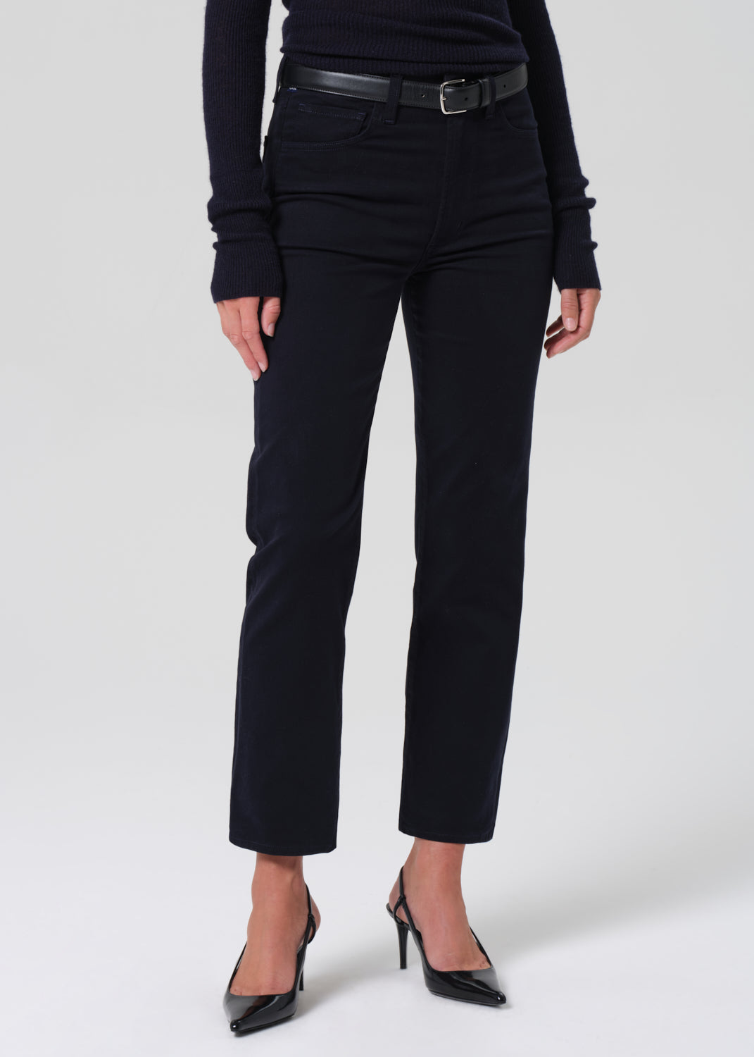 Person wearing a navy long-sleeve top and navy pants on a grey background