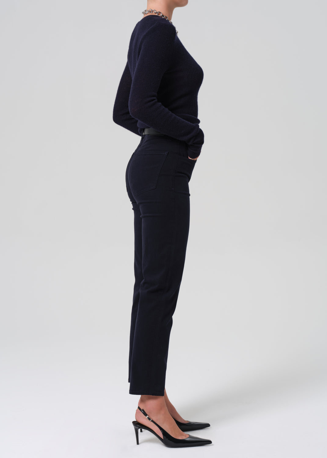 Person wearing a navy long-sleeve top and navy pants on a grey background