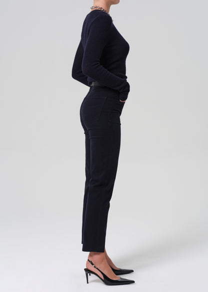 Person wearing a navy long-sleeve top and navy pants on a grey background