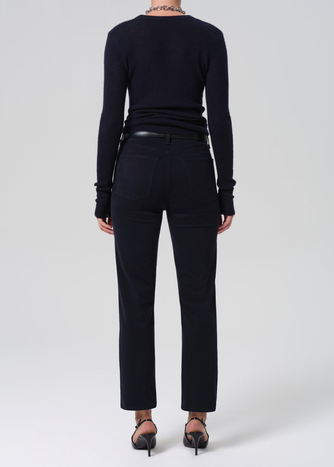 Person wearing a navy long-sleeve top and navy pants on a grey background