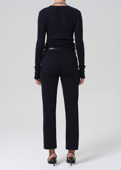 Person wearing a navy long-sleeve top and navy pants on a grey background