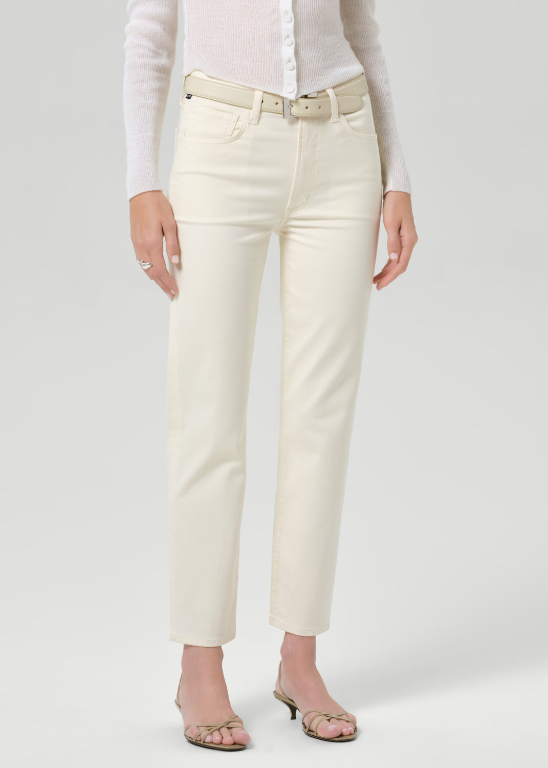 Person wearing white pants and a light-colored shirt on a plain background