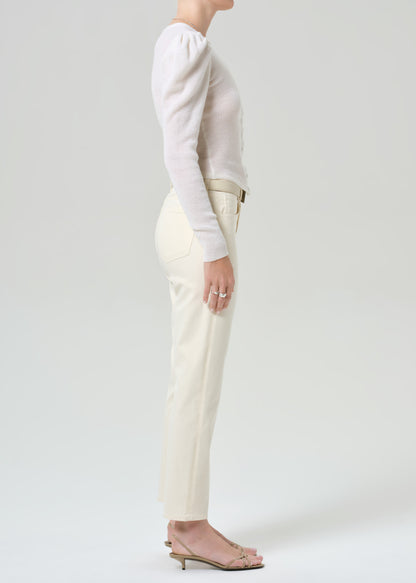 Person wearing a white sweater and cream pants on a plain background