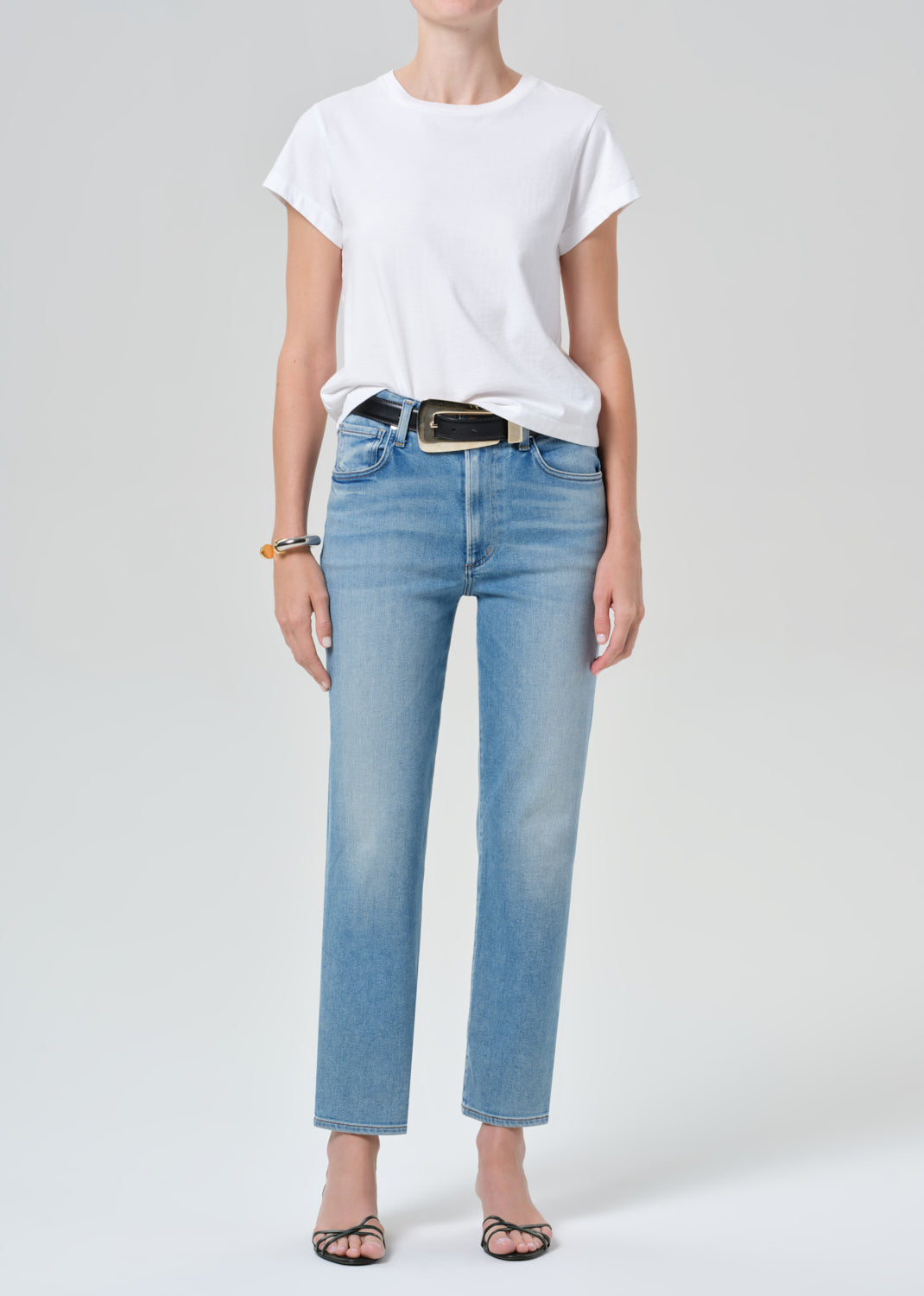 Person wearing a white t-shirt and light blue jeans on a plain background