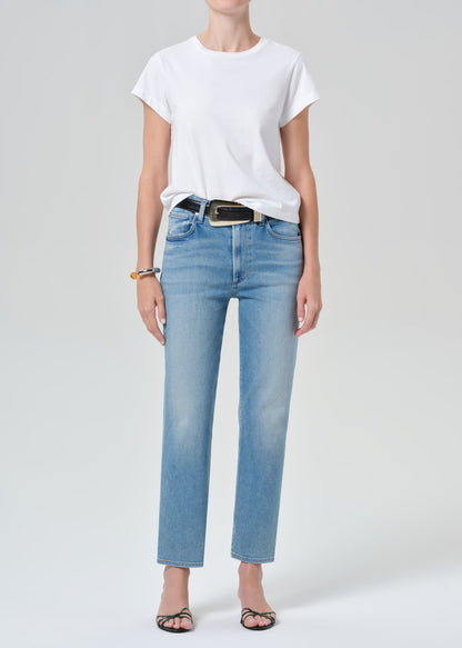 Person wearing a white t-shirt and light blue jeans on a plain background