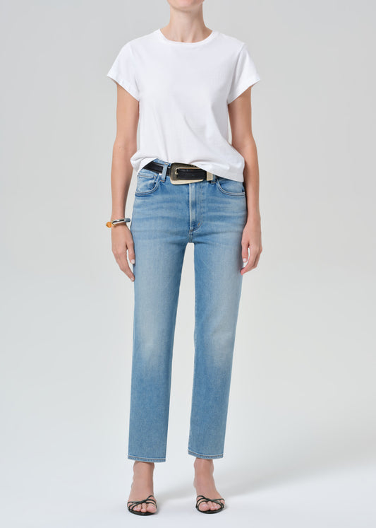 Person wearing a white t-shirt and light blue jeans on a plain background