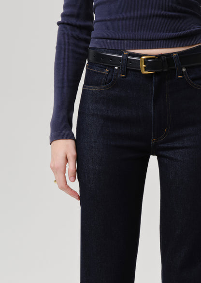 Person wearing dark blue jeans and a navy sweater on a grey background