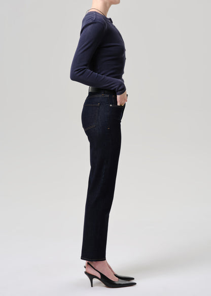 Person wearing a navy long-sleeve top and dark jeans on a grey background