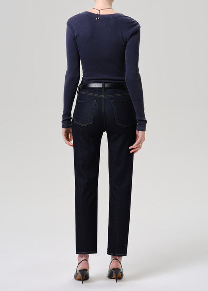 Person wearing a navy long-sleeve top and dark jeans on a grey background
