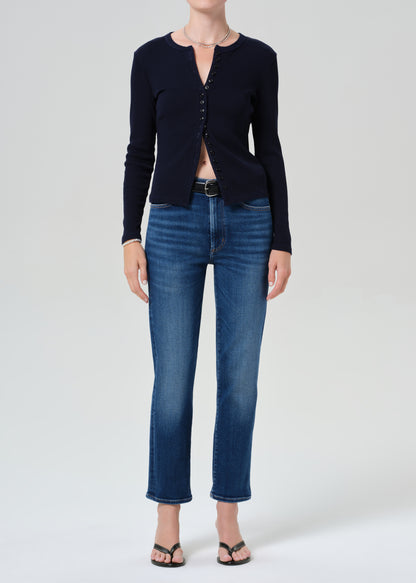 Person wearing a navy cardigan and blue jeans on a grey background